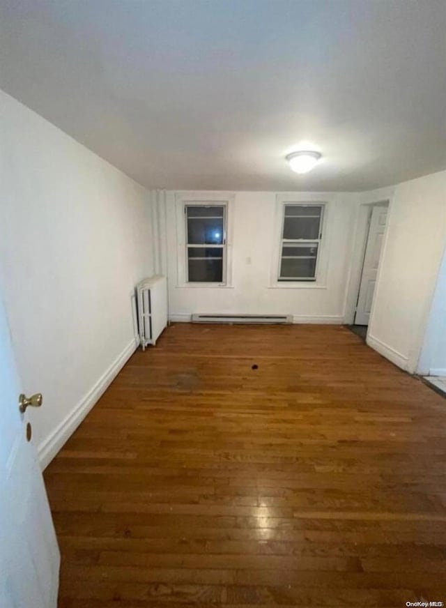 spare room with radiator, a baseboard radiator, and dark hardwood / wood-style floors