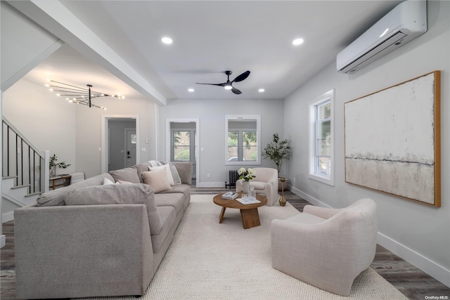 living room featuring a wall mounted air conditioner, ceiling fan with notable chandelier, and hardwood / wood-style flooring