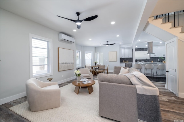 living room with hardwood / wood-style floors, a wall unit AC, ceiling fan, and sink