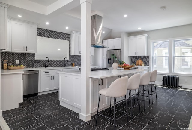 kitchen with white cabinets, decorative backsplash, stainless steel appliances, and radiator