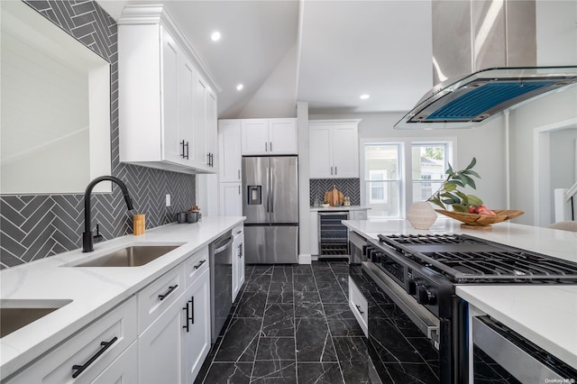 kitchen with decorative backsplash, stainless steel appliances, island range hood, sink, and white cabinetry