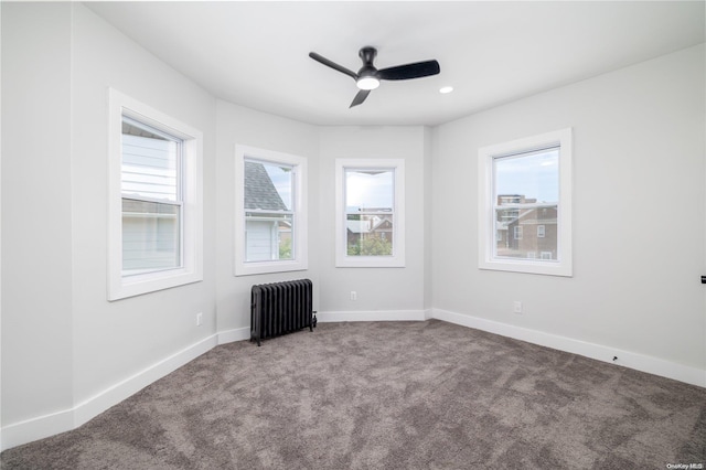 empty room with radiator heating unit, carpet floors, plenty of natural light, and ceiling fan