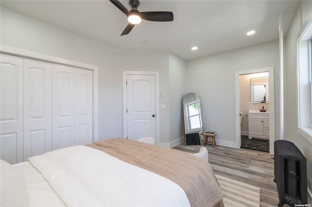 bedroom with a closet, ensuite bath, light hardwood / wood-style flooring, and ceiling fan