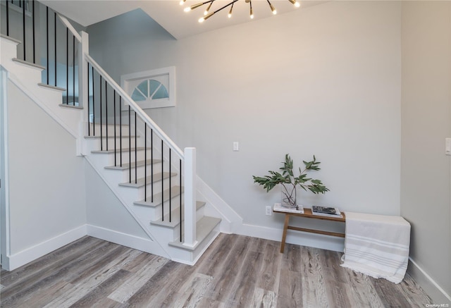 staircase with a chandelier and hardwood / wood-style floors