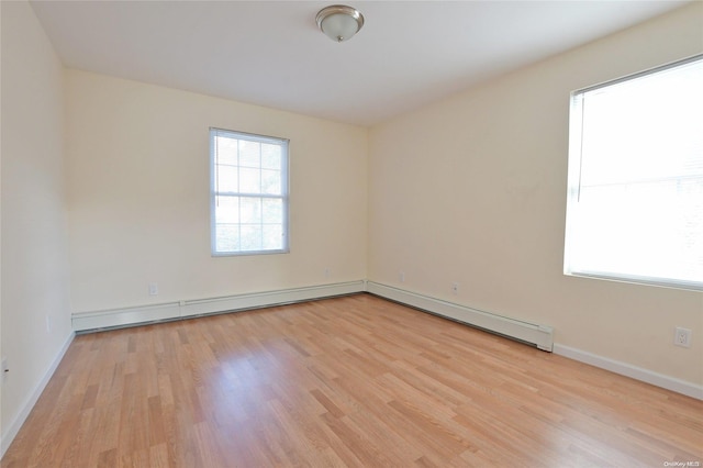 unfurnished room with baseboard heating and light hardwood / wood-style floors