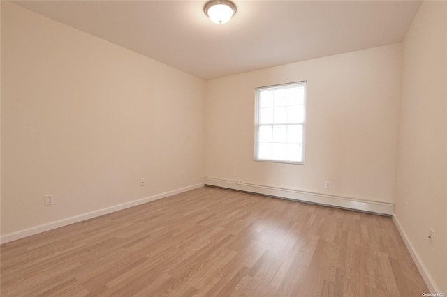 empty room with light hardwood / wood-style flooring and a baseboard heating unit