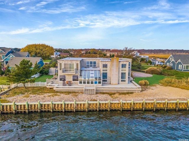 rear view of house with a yard and a deck with water view