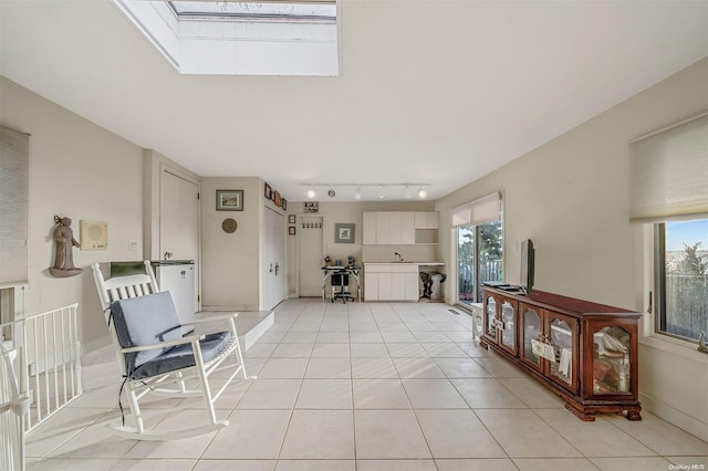 interior space featuring light tile patterned floors, a skylight, a healthy amount of sunlight, and sink