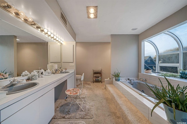 bathroom featuring tiled bath, vanity, and toilet