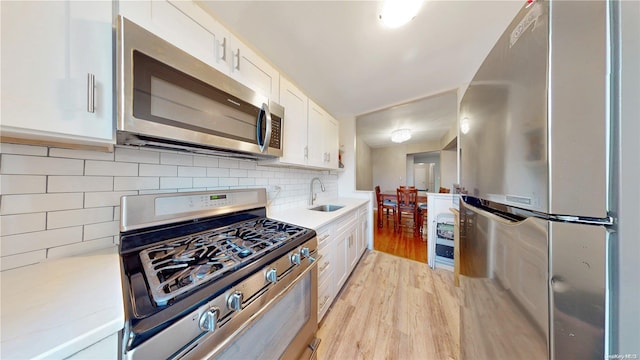 9707 4th Ave Unit 4G, Brooklyn, NY 11209 - kitchen featuring stainless steel appliances, light countertops, white cabinetry, light wood-style floors, and decorative backsplash