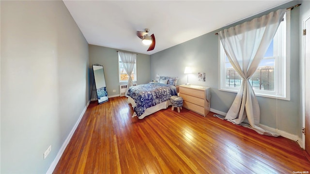 bedroom featuring wood-type flooring, radiator heating unit, and ceiling fan