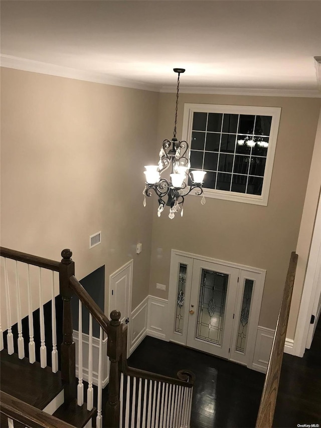 foyer entrance with dark hardwood / wood-style floors, crown molding, and a notable chandelier