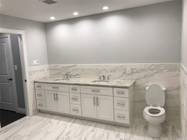 bathroom featuring vanity, toilet, and tile walls