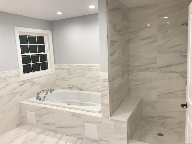 bathroom featuring a relaxing tiled tub and tile walls