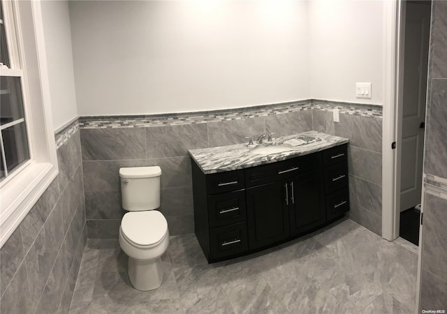 bathroom featuring vanity, tile walls, and toilet