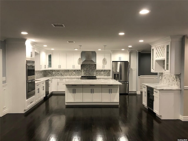 kitchen featuring wall chimney exhaust hood, dark hardwood / wood-style floors, pendant lighting, white cabinets, and appliances with stainless steel finishes