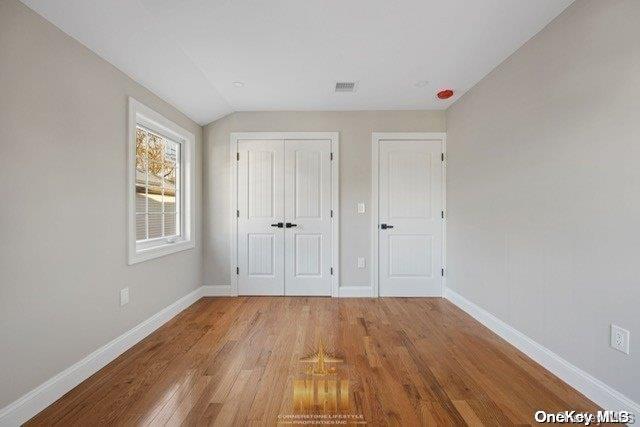 unfurnished bedroom featuring vaulted ceiling and light wood-type flooring