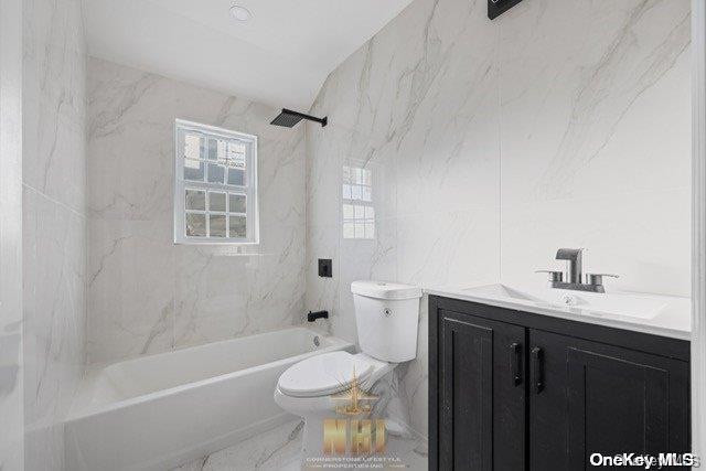 full bathroom with vanity, tiled shower / bath combo, tile walls, and toilet