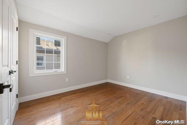 empty room featuring vaulted ceiling and hardwood / wood-style flooring