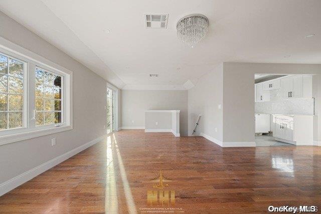 unfurnished living room featuring a chandelier and hardwood / wood-style floors