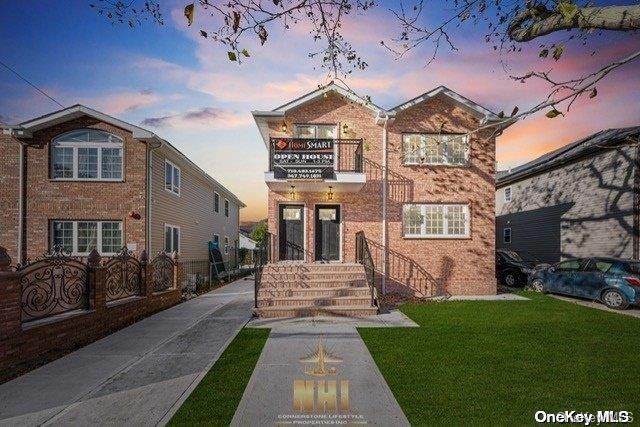 front facade featuring a balcony and a yard