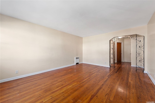 empty room with radiator heating unit and dark hardwood / wood-style floors