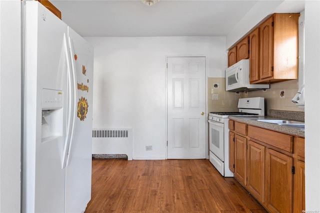 kitchen featuring light wood-type flooring, white appliances, radiator, and tasteful backsplash