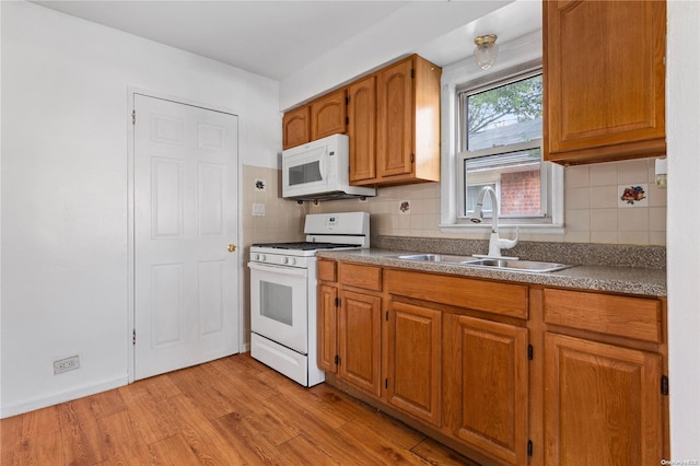 kitchen featuring backsplash, white appliances, sink, and light hardwood / wood-style flooring