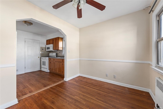 kitchen featuring dark hardwood / wood-style flooring, white appliances, radiator, and ceiling fan