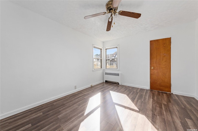 empty room featuring ceiling fan, radiator heating unit, dark wood-type flooring, and a textured ceiling