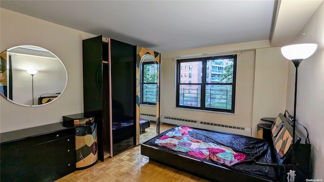 bedroom with light parquet floors and a baseboard heating unit