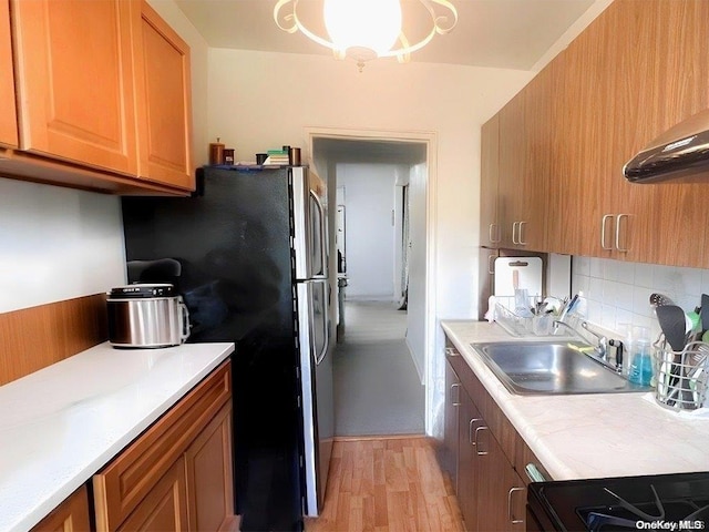 kitchen with sink, backsplash, stainless steel fridge, light hardwood / wood-style floors, and range