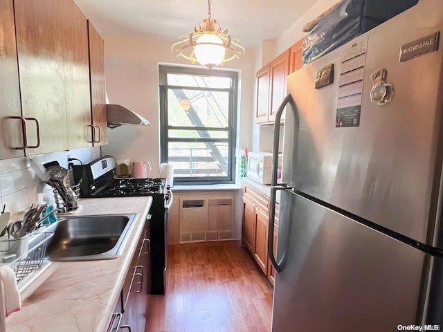 kitchen featuring dark hardwood / wood-style flooring, stainless steel appliances, exhaust hood, an inviting chandelier, and hanging light fixtures