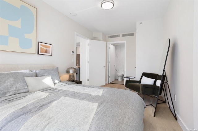 bedroom with light wood-type flooring and connected bathroom