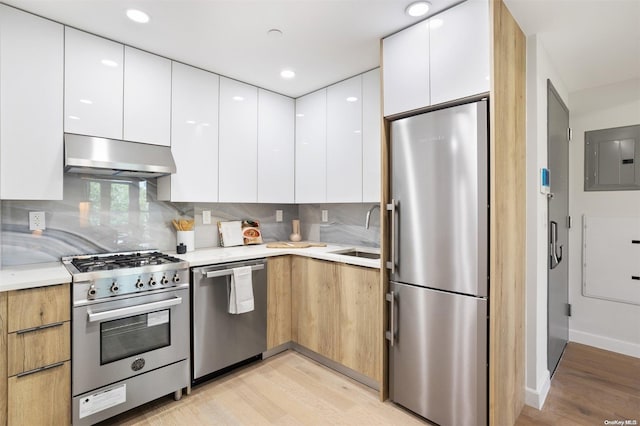 kitchen with white cabinetry, sink, stainless steel appliances, extractor fan, and light wood-type flooring