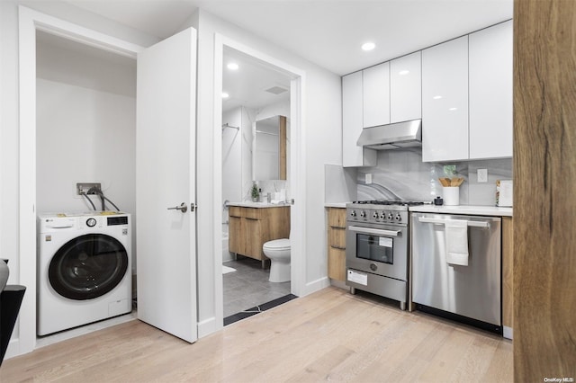 kitchen with light hardwood / wood-style flooring, white cabinets, stainless steel appliances, and washer / dryer