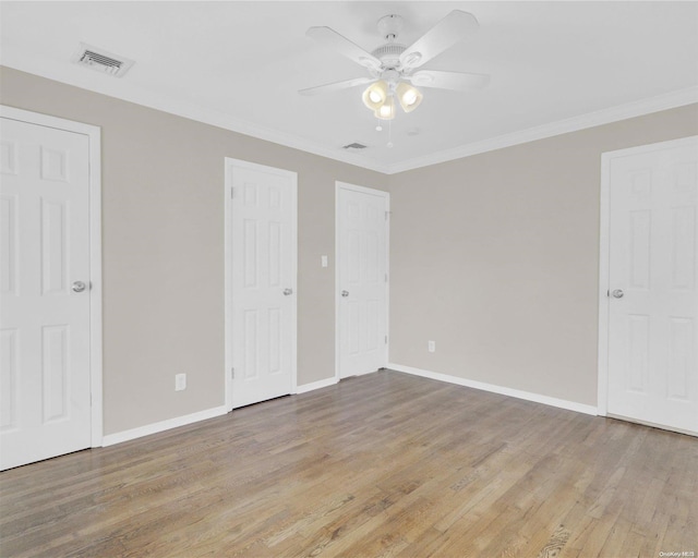 unfurnished bedroom with two closets, light hardwood / wood-style flooring, ceiling fan, and crown molding