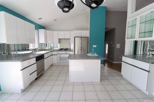 kitchen with appliances with stainless steel finishes, sink, light tile patterned floors, white cabinets, and a kitchen island