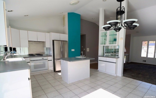 kitchen with light tile patterned floors, a chandelier, a kitchen island with sink, white cabinets, and appliances with stainless steel finishes