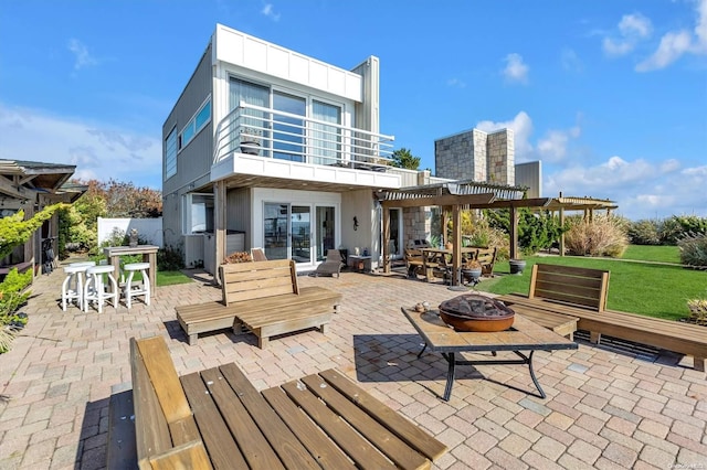 rear view of house featuring a fire pit, a balcony, a pergola, and a patio