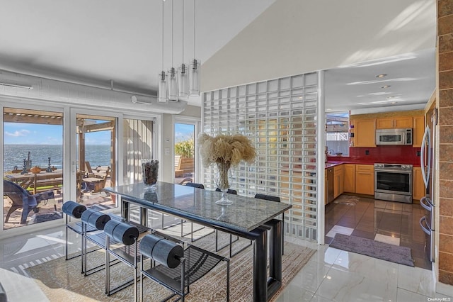 dining area with a water view, vaulted ceiling, and a healthy amount of sunlight