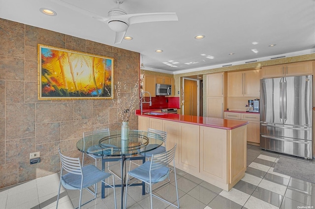 kitchen featuring appliances with stainless steel finishes, light tile patterned floors, tile walls, and sink