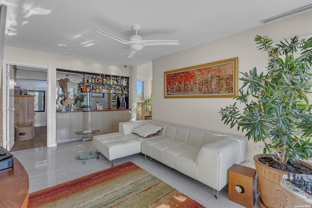 tiled living room featuring bar area and ceiling fan