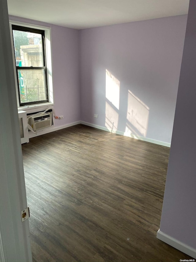 spare room featuring dark hardwood / wood-style flooring and an AC wall unit