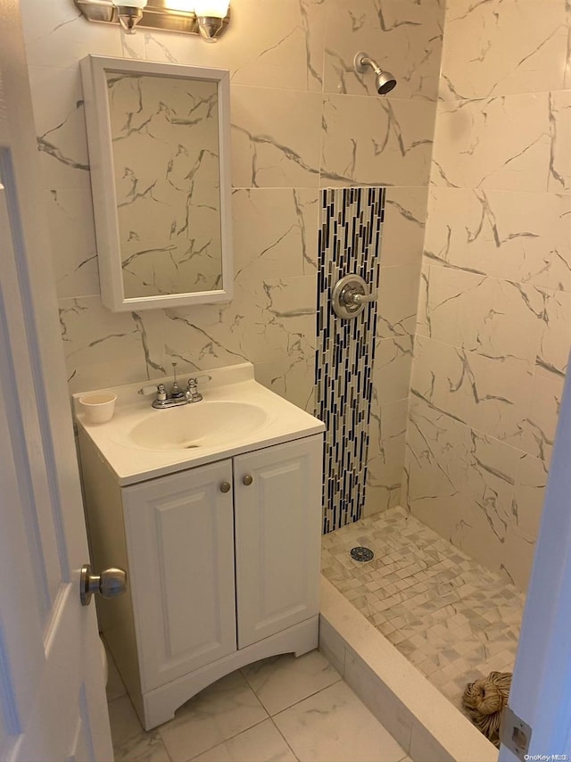 bathroom with a tile shower and vanity