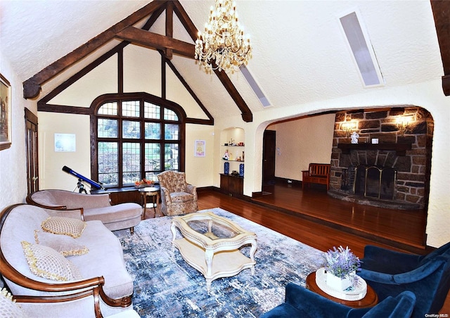 living room with beamed ceiling, wood-type flooring, a textured ceiling, and a stone fireplace