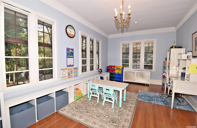 recreation room with a notable chandelier, dark hardwood / wood-style flooring, ornamental molding, and radiator