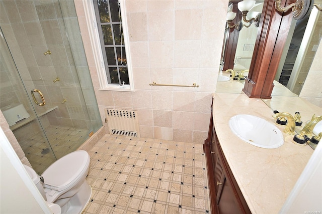 bathroom with radiator, vanity, tile walls, toilet, and a shower with shower door