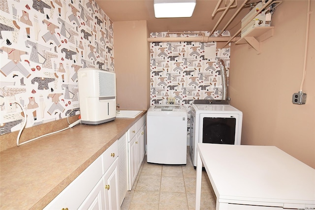 clothes washing area with cabinets, washing machine and dryer, sink, and light tile patterned flooring