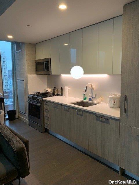 kitchen with dark wood-type flooring, sink, white cabinets, and range with gas stovetop